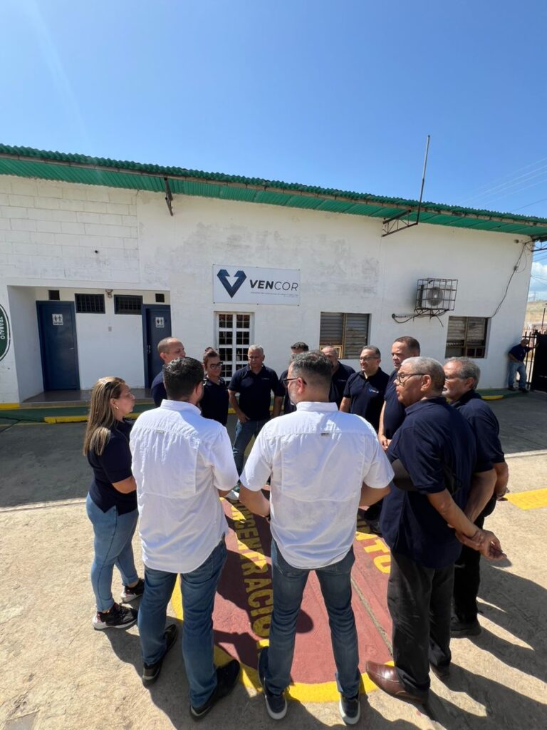 A group of people standing in a circle outside a building with a Vencor sign.